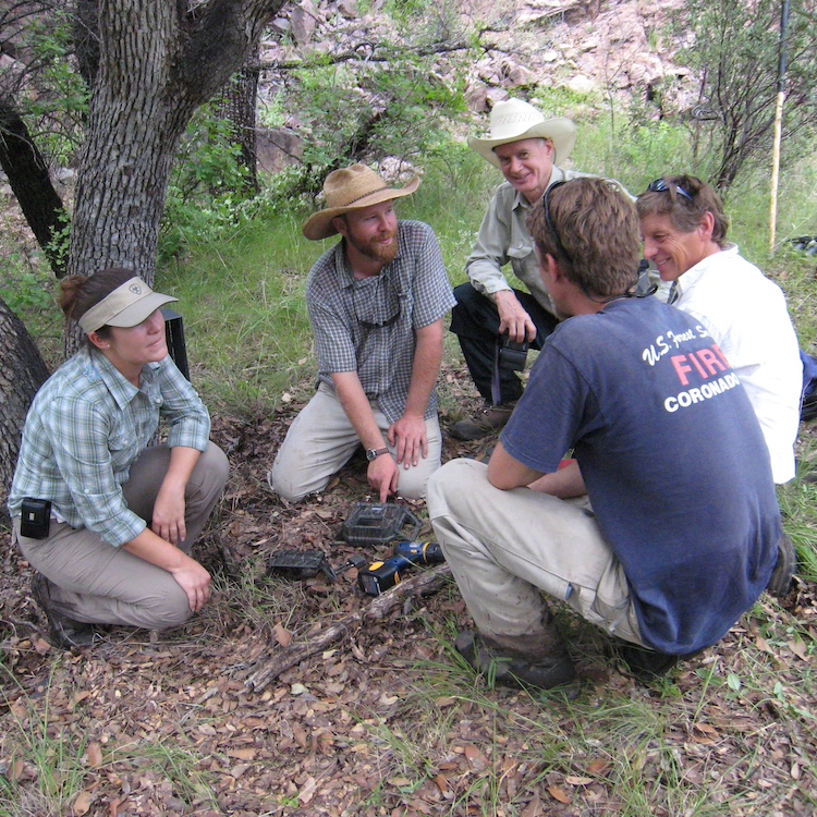 a group of students and professors inspecting an item during field research